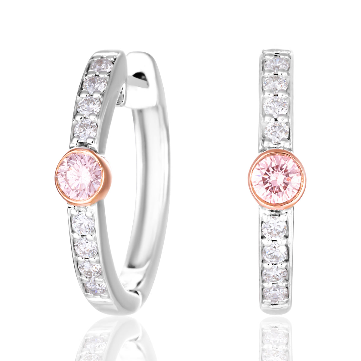 A pair of silver huggie hoop earrings with a row of clear pavé stones and a central round pink gemstone in a rose gold setting, shown on a white background with a soft reflection.