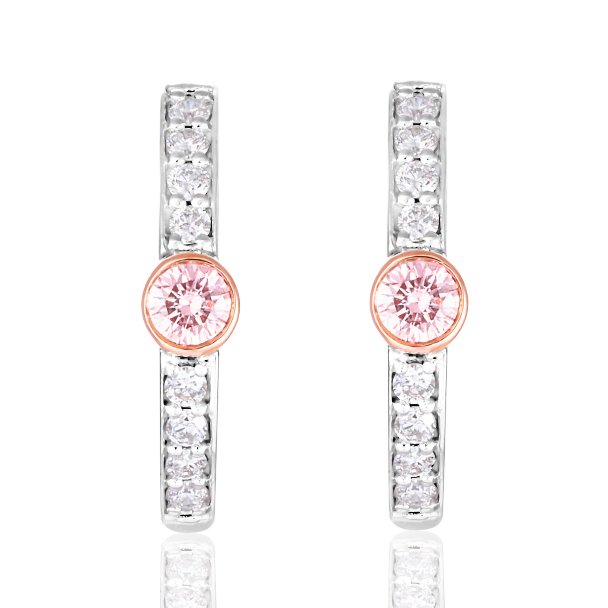 A pair of silver-toned huggie hoop earrings featuring a central round pink gemstone surrounded by a rose gold bezel, with additional clear round-cut stones set along the vertical bars, shown on a white background with a soft reflection.