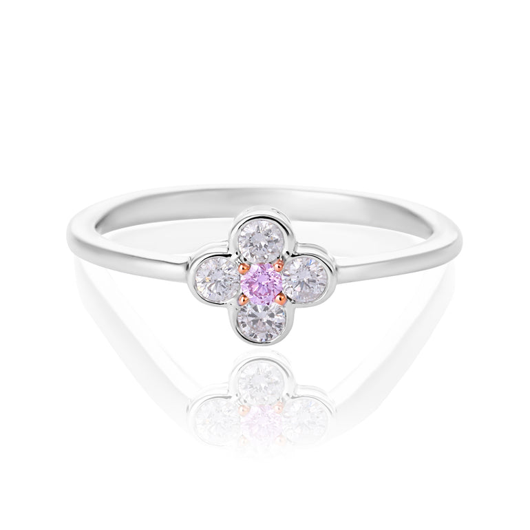 A pink diamond flower ring featuring a central round pink gemstone surrounded by four clear round-cut stones, set on a polished silver band, shown on a white reflective background.