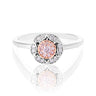 A white gold and rose gold ring with a central round rose gold gemstone surrounded by a halo of small clear stones, set against a white background with a soft reflection below.