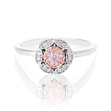 A white gold and rose gold ring with a central round rose gold gemstone surrounded by a halo of small clear stones, set against a white background with a soft reflection below.