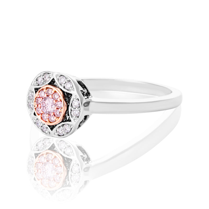 A halo ring featuring a central rose gold cluster of round-cut pink stones surrounded by clear stones, shown on a reflective white background.